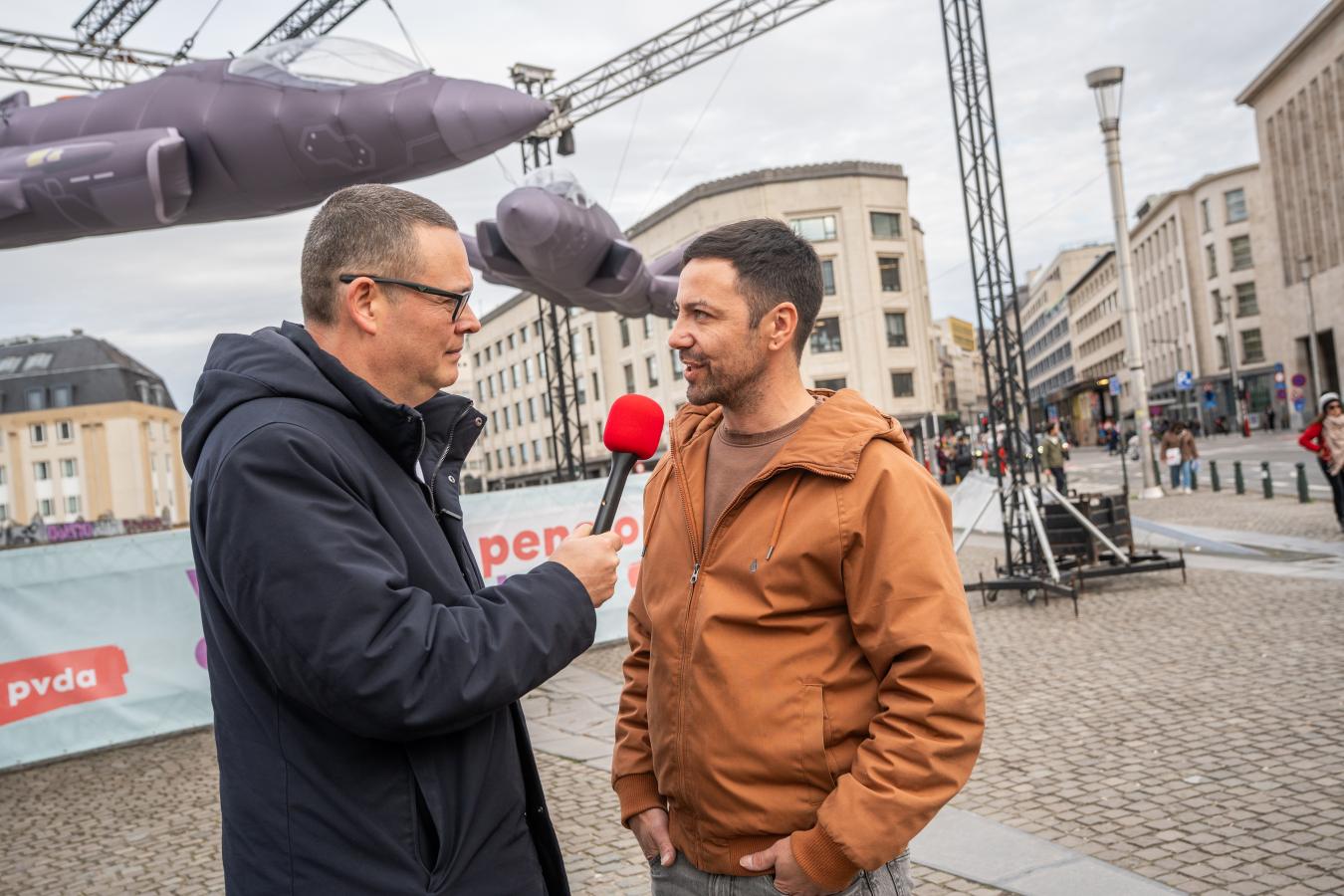 Raoul Hedebouw tend le micro pour interviewer un homme