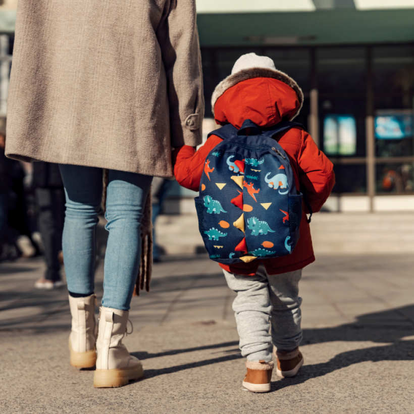 Un enfant tenant la main à une adulte devant l'entrée de l'école