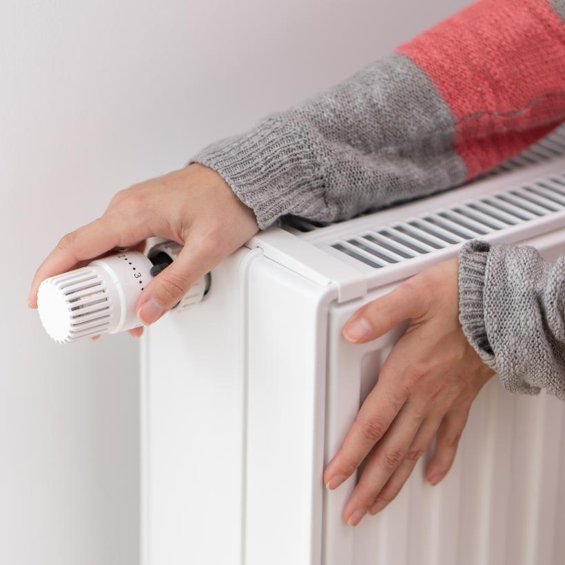 Une personne en pull allume le radiateur.