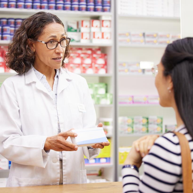 Apotheekster houdt een medicamentendoos vast van het witte product.
