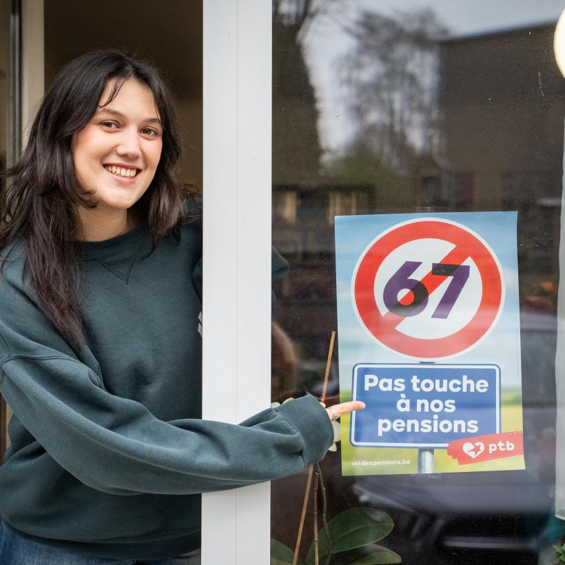 Une jeune femme montre du doigt l'affiche du PTB contre le vol des pensions.